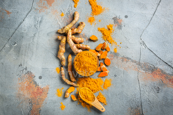 t. Raw organic orange turmeric root and powder, curcuma longa on a grunge cooking table. Indian oriental low cholesterol spices. Top view flat lay
