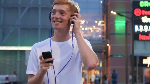 Man Listening Music In Headphones With Phone Near Shopping Mall