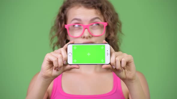 Young Beautiful Nerd Woman Thinking While Showing Phone