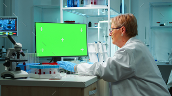 n modern equipped lab at night. Team of microbiologists doing vaccine research writing on device with green screen, isolated, mockup display.