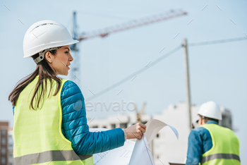 Selective focus of surveyors with blueprint on construction site