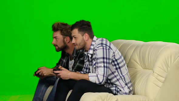 Two Guys Playing Video Games with Wireless Control Pad. Green Screen