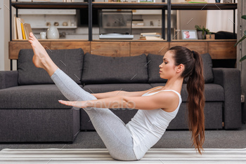 woman practicing boat pose at home in living room