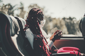 with long braided hair of red color is sitting on a leather seat of a regular intercity bus and watching an online show using her smartphone