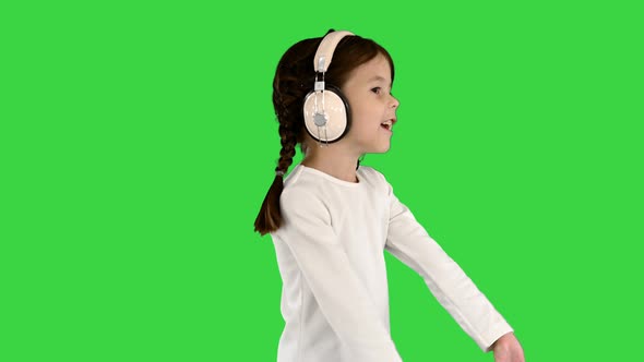 Excited Little Girl Dressed in White Listening To the Music in Headphones and Singing Along on a