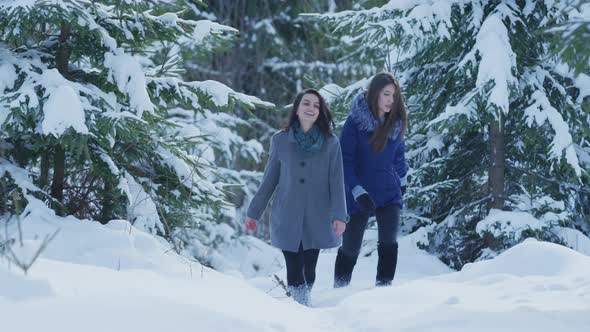 Two girls walking in the forest in winter