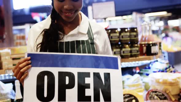 Female staff holding open signboard in organic section