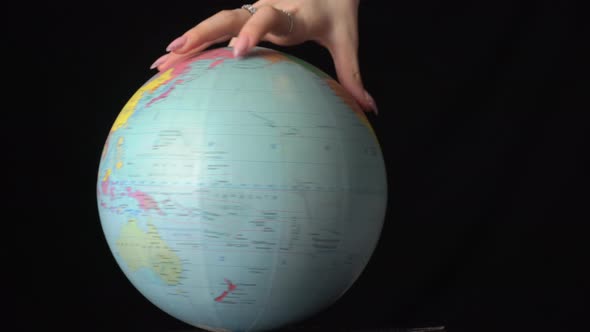 Geographical Globe is Twisted Around Its Axis By a Female Hand