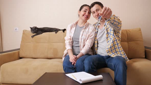 Family Shows Keys Sitting with Cute Cat on Sofa in Room