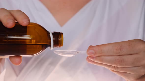 Cough Syrup is Poured Into Transparent Spoon