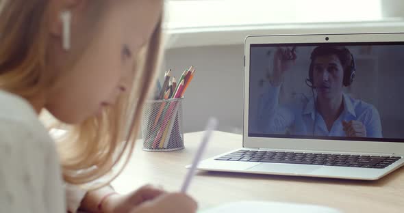 Smart Little Girl Uses Laptop for Video Call with Online Teacher. Screen Shows Video Lecture with