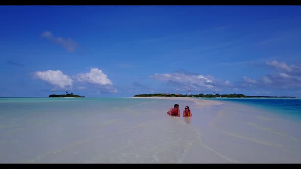 Guy and girl sunbathe on tranquil tourist beach holiday by blue green lagoon and white sand backgrou