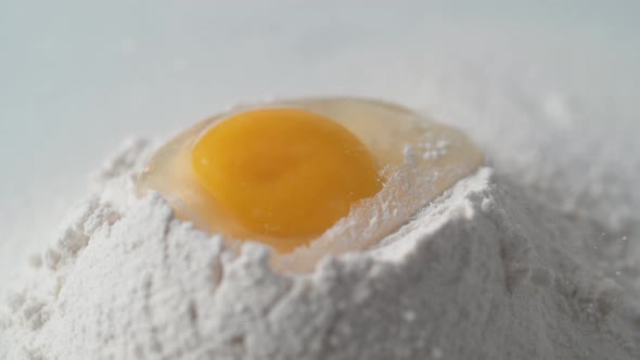 Egg falls on a pile of flour. Slow Motion.