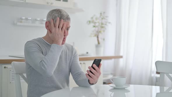 Sad Senior Old Man Having Failure on Smartphone at Home