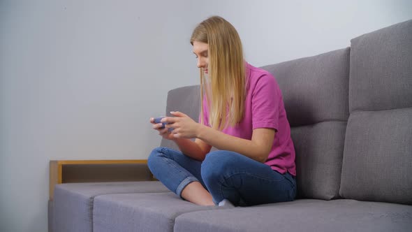 Young female playing games on mobile phone at home in 4k stock video