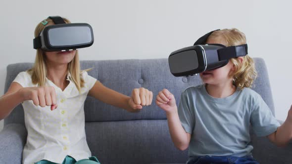 Caucasian brother and sister gesturing while using vr headset sitting on the couch at home
