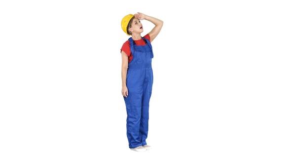 Engineer woman in yellow helmet looking up amazed at a