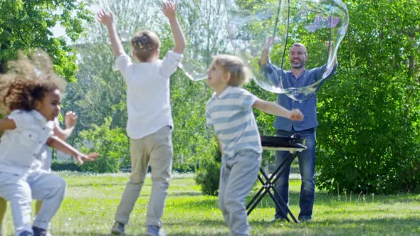 Man Making Giant Bubbles for Kids in Park