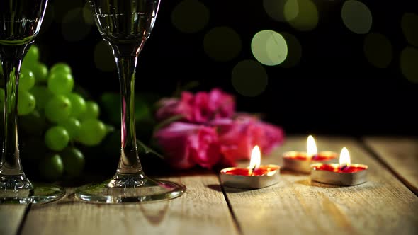 Love Still Life in Macro Made of Burning Candles and Flowers Lying Next to Grape with Wineglasses