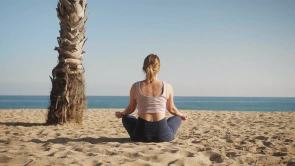 Woman Doing Yoga Meditation on the Beach