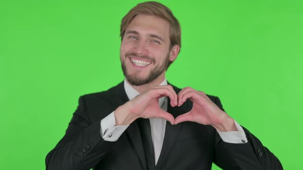 Young Businessman Showing Heart Shape By Hands on Green Background