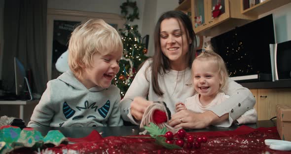 Cheerful Family Making Handmade Christmas Gift and Playing Together