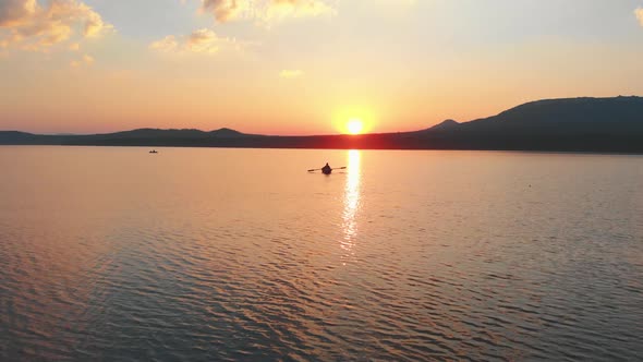 Man Sailing on the Boat with Paddles on the River While the Sunset - Beautiful Landscape