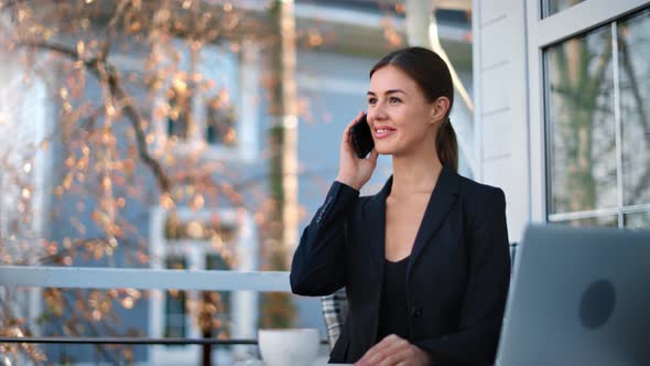 Happy Businesswoman Talking Smartphone at Street Cafe Terrace