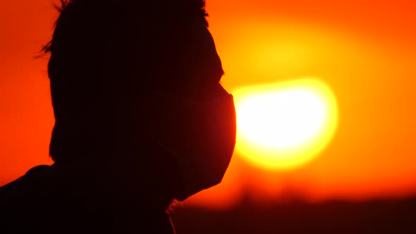 Silhouette Profile of a Young Man in a Mask. Male Removes a Protective Disposable Medical Mask From