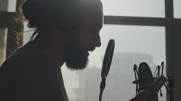 Recording of a Young Bearded Caucasian Singer in Front of a Microphone at Home