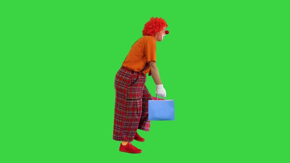 Funny Clown with Heavy Shopping Bags Walking on a Green Screen, Chroma Key