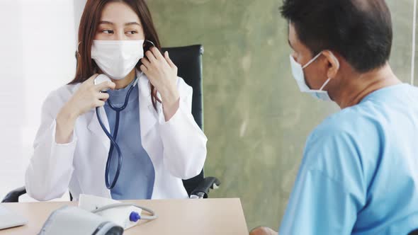 Asian woman doctor with face mask checks stethoscope health of an elderly handicapped