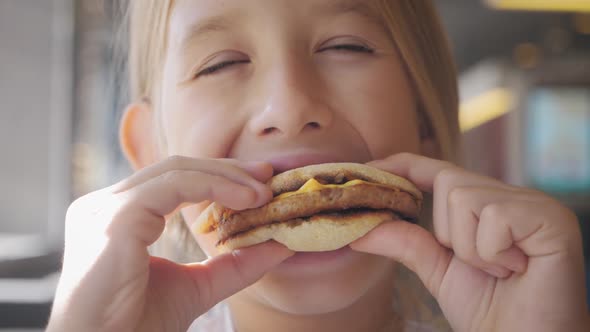 Beautiful Happy Hungry Baby Girl Eating Hamburger. Fast Food Concept. Tasty Unhealthy Burger