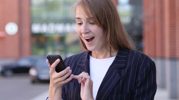 Business Woman Celebrating Success While Using Smartphone
