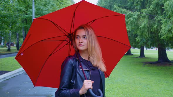 Beautiful Girl with Red Umbrella Stands in the Park