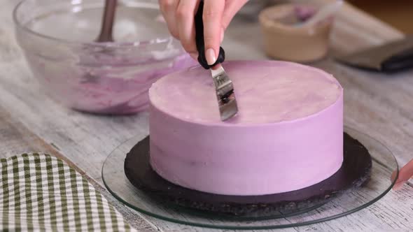 The process of decorating a cake with purple cream cover.