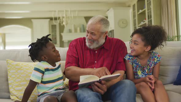 Grandfather and grandchildren reading book at home