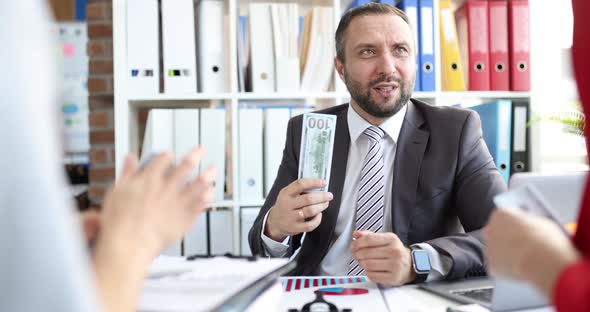 Happy Businessman in the Office Waving Dollars