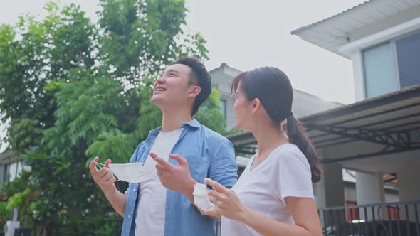 Asian attractive couple standing in front of their house and take deep breathing after removing mask