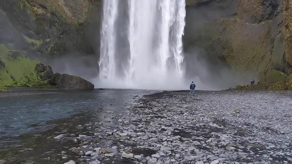 Skogafoss Waterfall in Iceland in Summer with man walking along river