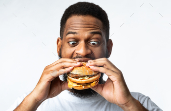  White Studio Background. Black Man Enjoying Hamburger Overeating Junk Food. Nutrition And Unhealthy Fastfood, Binge Eating Habit Problem Concept