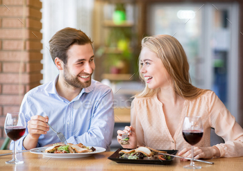 Lovely lady with her boyfriend eating salad and drinking wine, celebrating anniversary together at / Photodune, Misc