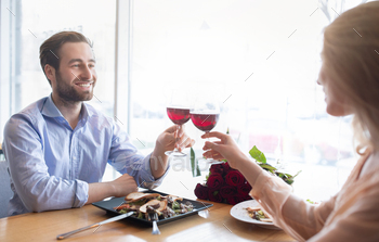 Affectionate millennial couple celebrating anniversary together, drinking wine, making toast at cozy / Photodune, Misc