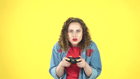 Girl Playing a Video Game Using a Wireless Controller on Yellow Background, Slow Motion