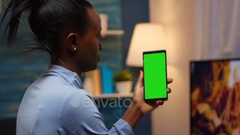  hand looking at mockup. Reading on green screen template chroma key isolated mobile phone display using techology internet sitting on cozy couch
