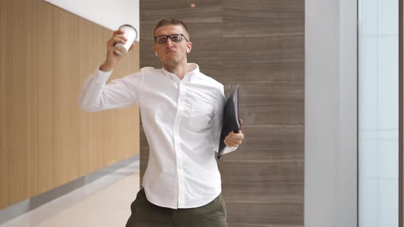 Funny Businessman With Coffee Cup Dancing In Wireless Airpods In Office Hall