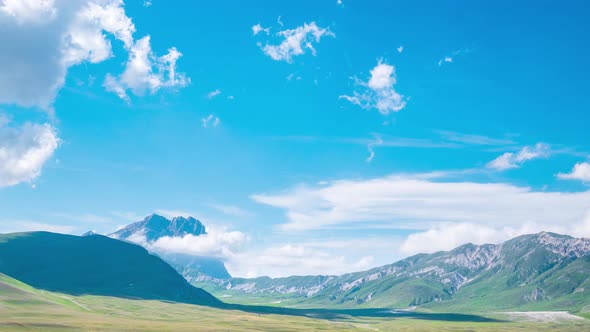 Time lapse: clouds moving in blue sky, sunny day on the mountains, view point over rocky mountain pe