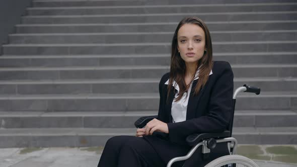 Portrait of Handicapped Serious Businesswoman in Suit Sitting in Wheelchair at Street