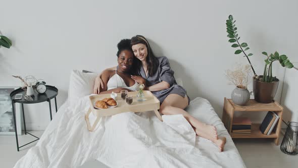 Portrait of Happy Lesbian Couple Eating Breakfast in Bed