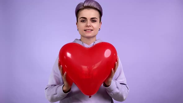 Young Adult Woman Holding Red Balloon Imitating Heart Beating Indoors